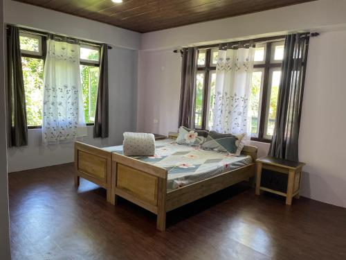 ein Schlafzimmer mit einem Bett in einem Zimmer mit Fenstern in der Unterkunft KHIMSHA HOMESTAY in Pelling