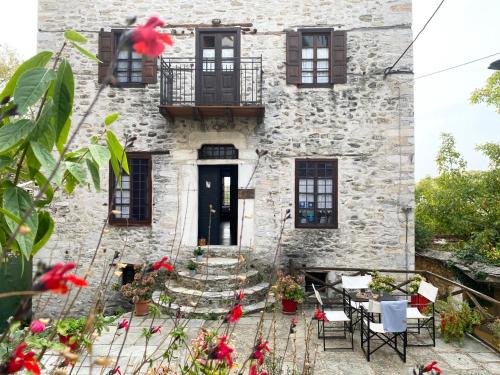 una casa de piedra con flores rojas delante de ella en Alatinos, en Pinakátai