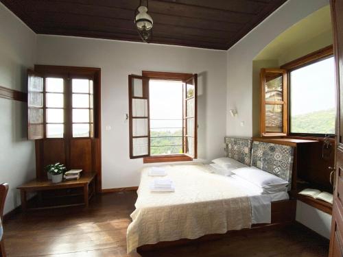 a bedroom with a large bed and two windows at Alatinos in Pinakátai