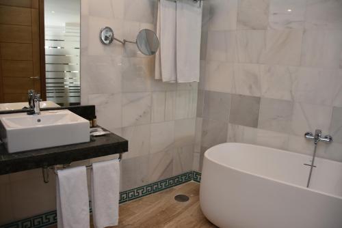 a bathroom with a tub, sink and mirror at Hotel Doña Lola Zahara in Zahara de los Atunes