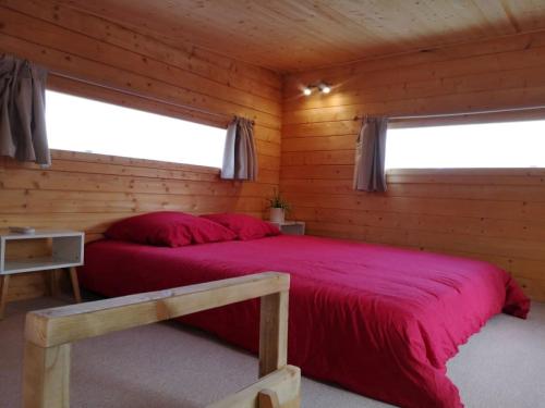 - une chambre avec un lit rouge dans une cabane en rondins dans l'établissement Le Petit Chalet de Nîmes Shantay Youstay, à Nîmes