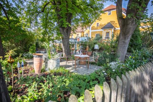 a garden in front of a yellow house with a wooden fence at Donauwirt - Hotel garni in Weissenkirchen in der Wachau