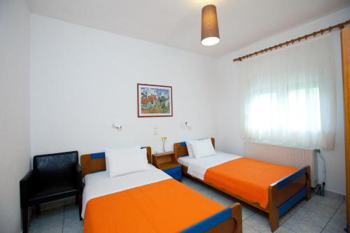 pokój z 2 łóżkami i krzesłem w obiekcie Yiouli Hotel w mieście Kokino Nero