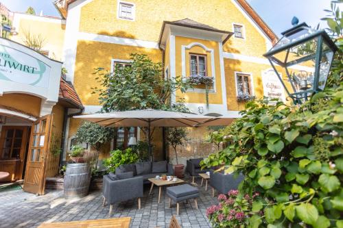 a patio with chairs and an umbrella in front of a building at Donauwirt - Hotel garni in Weissenkirchen in der Wachau