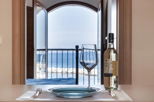 una mesa con un plato y una copa de vino y una ventana en La Vecchia Scuola en Cavo