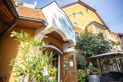 a yellow building with an entrance with an umbrella at Donauwirt - Hotel garni in Weissenkirchen in der Wachau
