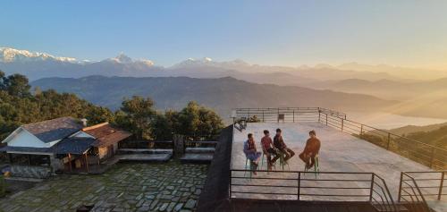 a group of people walking on a roof with mountains in the background at Pumdikot Mountain Lodge in Pokhara