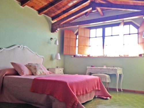 Un dormitorio con una cama con una manta rosa y una mesa en Villa Margiò, en Torri del Benaco
