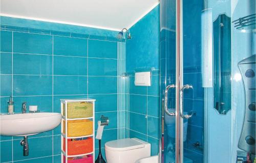 a blue tiled bathroom with a toilet and a shower at Villa Oceania in Mandra Capreria