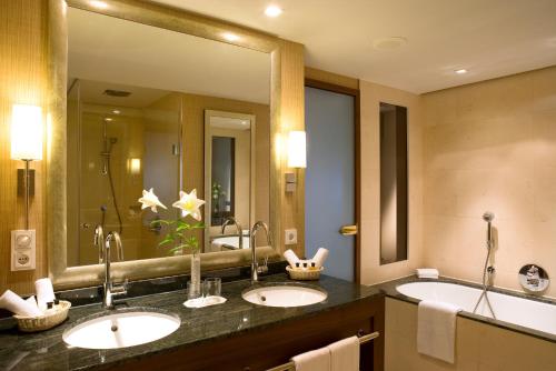 a bathroom with two sinks and a large mirror at Pullman Cologne in Cologne
