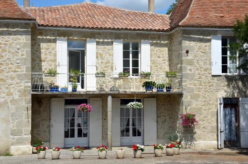 a stone house with potted plants and windows at Chez Madeleine in Saint-Colomb-de-Lauzun
