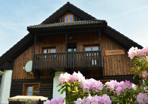 a wooden house with a balcony and pink flowers at Penzion U Horejšů, Zadov - Churáňov in Stachy
