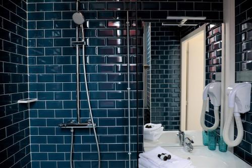 a blue tiled bathroom with a sink and a mirror at Hôtel Argia in Hasparren