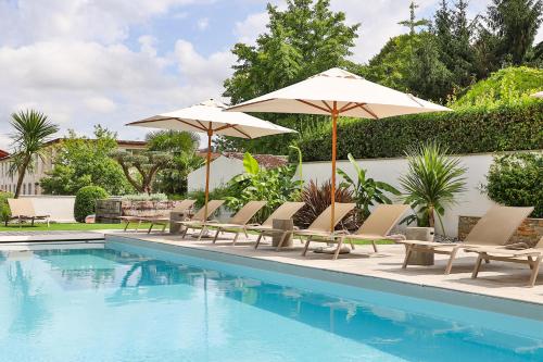 - un groupe de chaises longues et de parasols à côté de la piscine dans l'établissement Hôtel Argia, à Hasparren