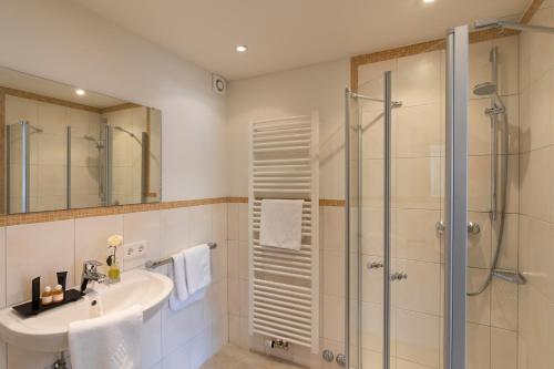 La salle de bains est pourvue d'un lavabo et d'une douche. dans l'établissement Hotel Garni Bergidyll - adults only, à Pfronten