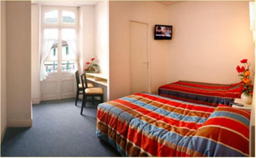 a hotel room with a bed and a desk at Hôtel Métropole in Lourdes