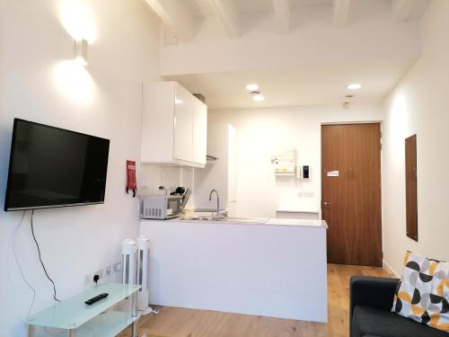 a living room with a kitchen and a tv on a wall at Leather Lane Serviced Apartments in London