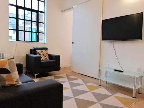 Leather Lane Serviced Apartments في لندن: غرفة معيشة مع أريكة وتلفزيون على الحائط