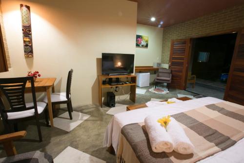 a hotel room with a bed and a table and a television at Pousada Sítio Ipê in Viçosa do Ceará