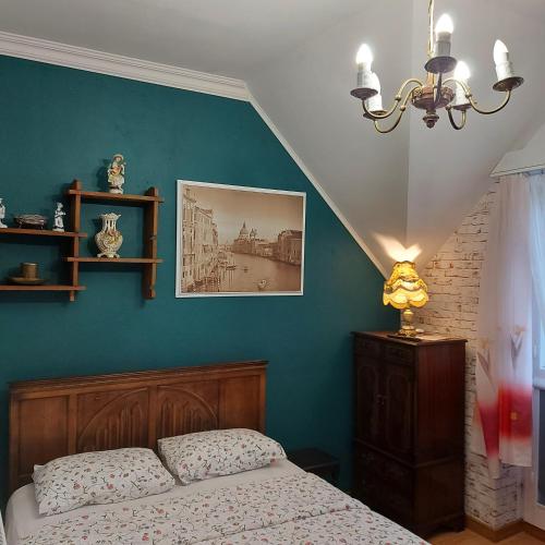 a bedroom with a bed and a blue wall at Willa Zamkowisko in Gołubie