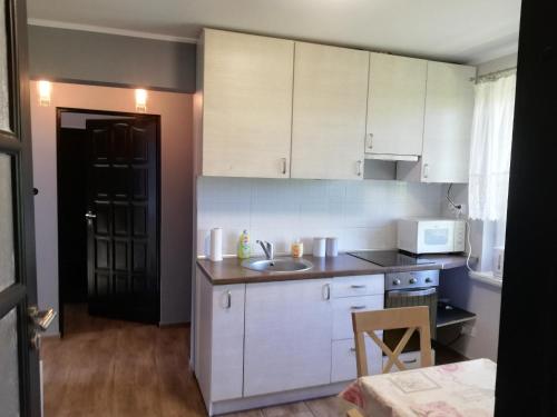una cocina con armarios blancos y fregadero en Leśny Apartament, en Szczytno