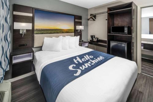 a hotel room with a large bed with a large window at Days Inn by Wyndham Galt - Elk Grove South in Galt