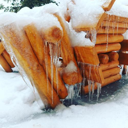 a pile of logs covered in snow with icicles at Willa Zamkowisko in Gołubie