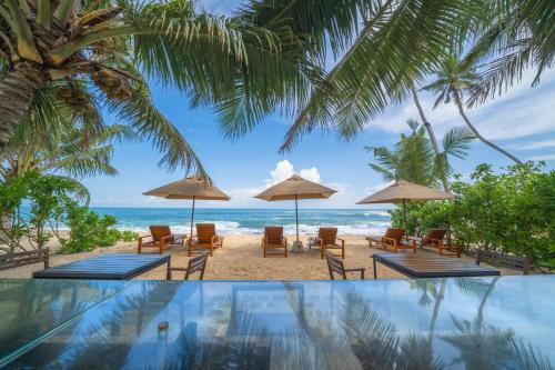 a view of a beach with chairs and umbrellas at Three Gables Boutique Villa in Mirissa