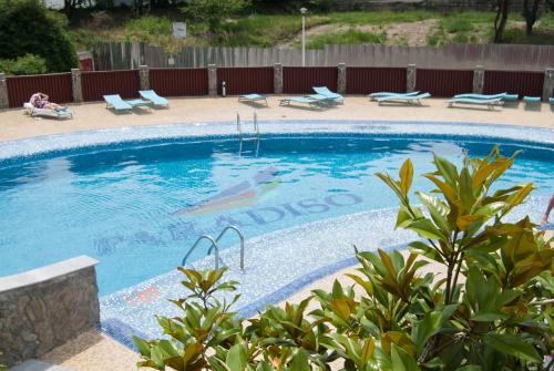 a large swimming pool with a woman sitting on lounge chairs next to it at Hotel Paradiso in Mangalia