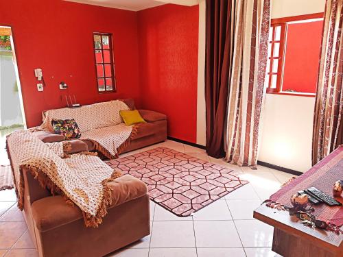 a living room with red walls and brown furniture at Ubatuba Beach House in Ubatuba