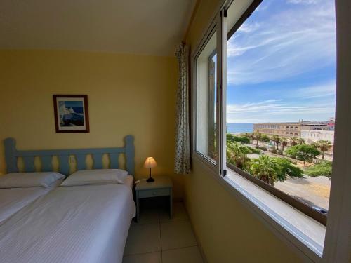 a bedroom with a large window with a view of the ocean at Apartments Bambu in San Agustin