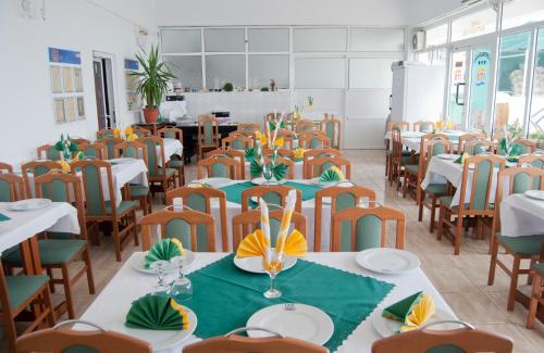 a dining room with tables and chairs with green napkins at Hotel Cerna in Saturn