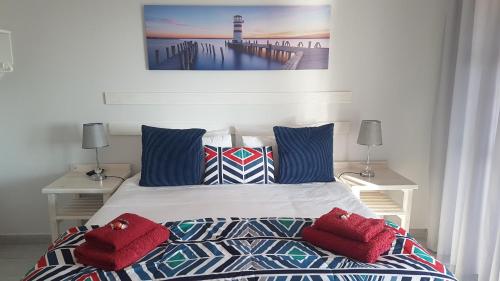 Jeffreys Bay的住宿－OCEAN VIEW GUEST HOUSE，一间卧室配有一张带红色枕头的床和一座灯塔。