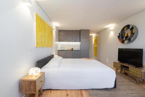 ein Schlafzimmer mit einem großen weißen Bett und einem TV in der Unterkunft Domus 21 - Batalha in Porto
