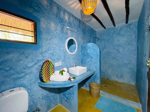 a blue bathroom with a sink and a mirror at Oleza Boutique Hotel Zanzibar in Michamvi