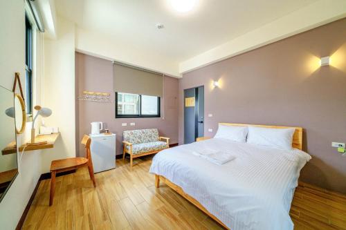 花蓮市的住宿－陸口壹家，卧室配有一张白色大床和一把椅子