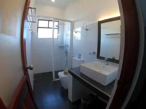 bagno con lavandino, servizi igienici e specchio di The Bay ad Arugam