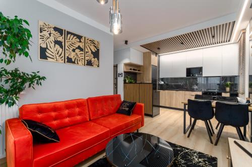 a living room with a red couch and a kitchen at Apartament Eveline in Rzeszów