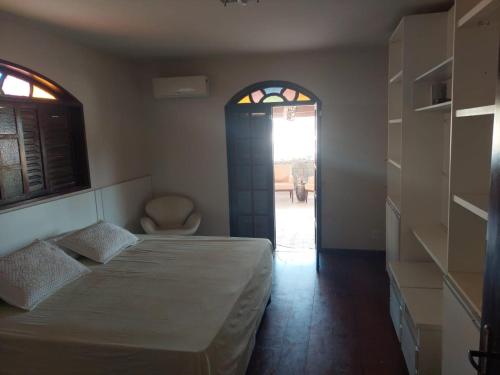 1 dormitorio con cama, ventana y silla en Casa das Dunas, en Tamoios