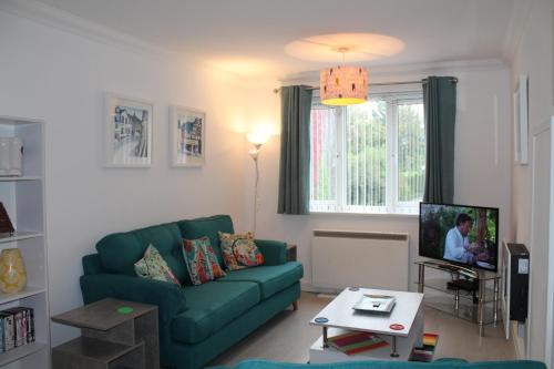 a living room with a green couch and a tv at BONNIE'S APARTMENT, adults only in Bowness-on-Windermere