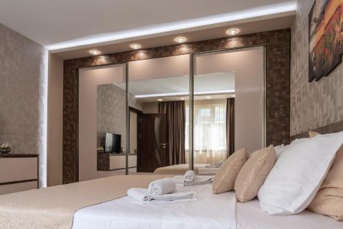 een slaapkamer met een wit bed en een grote spiegel bij Apartment Central-LUX in Veliko Tŭrnovo