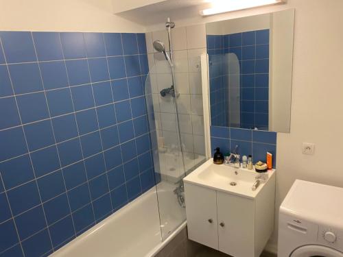 ein Badezimmer mit einem Waschbecken und einer Dusche mit blauen Fliesen in der Unterkunft LE VELODROME Chic appartement in Marseille