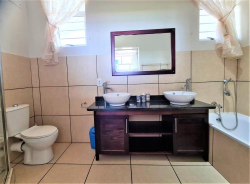 a bathroom with two sinks and a toilet and a mirror at Colonial Sands B in Margate