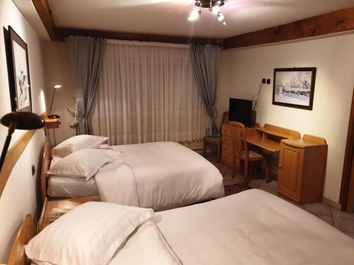 a hotel room with three beds and a desk at Hotel Restaurant Du Faudé in Lapoutroie