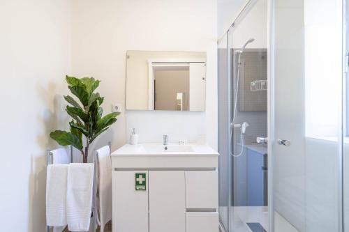 y baño blanco con lavabo y ducha. en Domus 21 - Entreparedes en Oporto