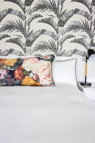 a bedroom with a white bed with a floral wallpaper at Villa Le Roc Kleinmond Accommodation in Kleinmond