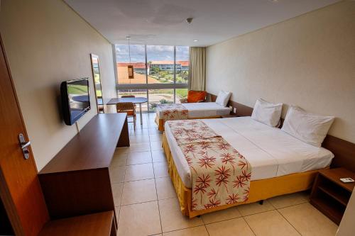 a hotel room with two beds and a television at Villa Hípica Resort in Gravatá