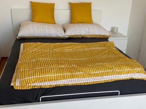 Cama con sábanas y almohadas amarillas y negras en Seevilla Matilda direkt am Ufer, en Jois