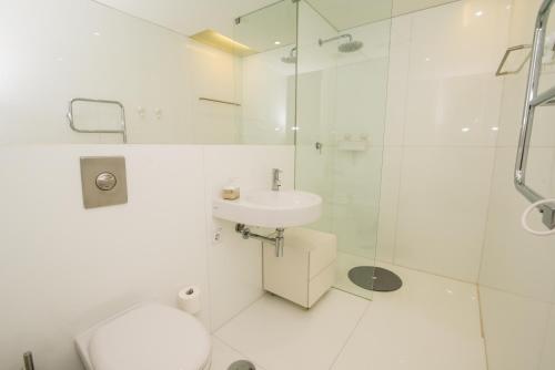 a white bathroom with a shower and a sink at Convento das Bernardas By Algartur (AL) in Tavira