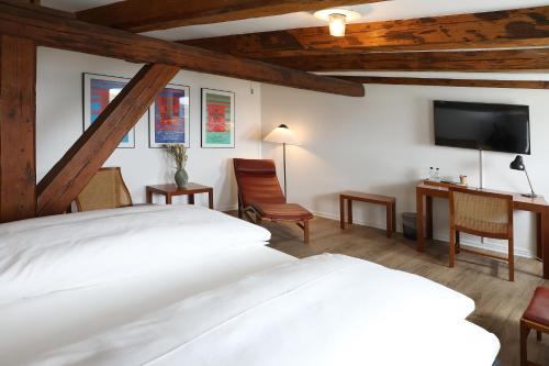a bedroom with a bed and a desk and a tv at Hotel Steenbergs in Nykøbing Mors